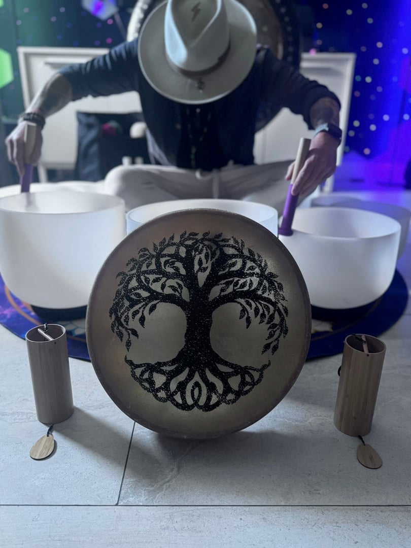 Close up of woman's hand playing singing bowl during group meditation session with copy space. Brass sound bowl used for healing and energy work at indoor wellness retreat. Peaceful spiritual practice with focus and intention with tibetan bells.