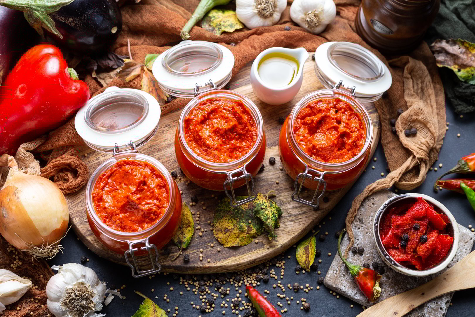 A high angle view of jars with raw ajvar on the table with vegetables under the lights