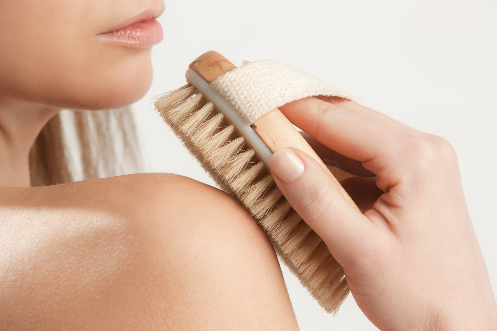 Dry body brush, Woman dry brushing body to reduce cellulite, detoxify the lymphatic system, and achieve beautiful smooth skin.