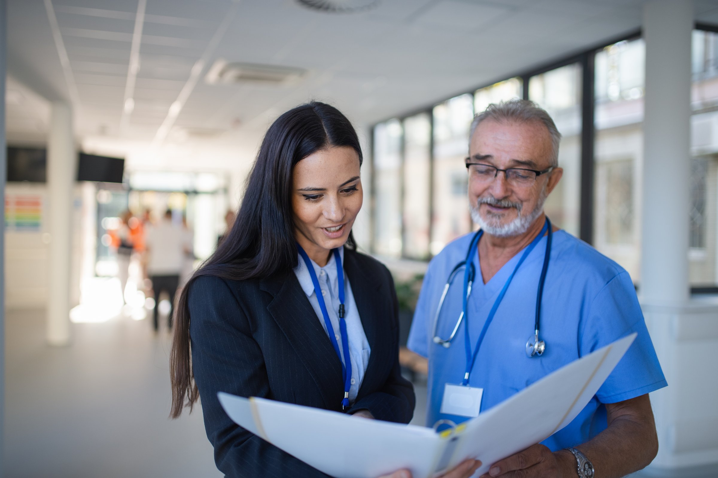 Doctor and business woman in hospital reading documents in a hospital corridor.