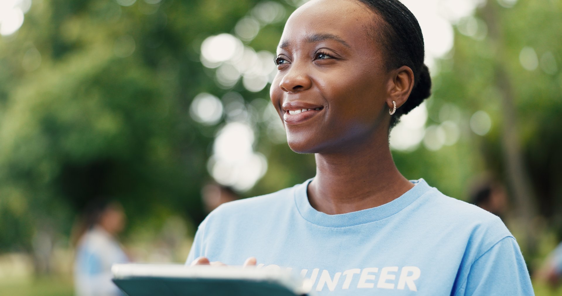 Woman volunteer thinking with tablet in park