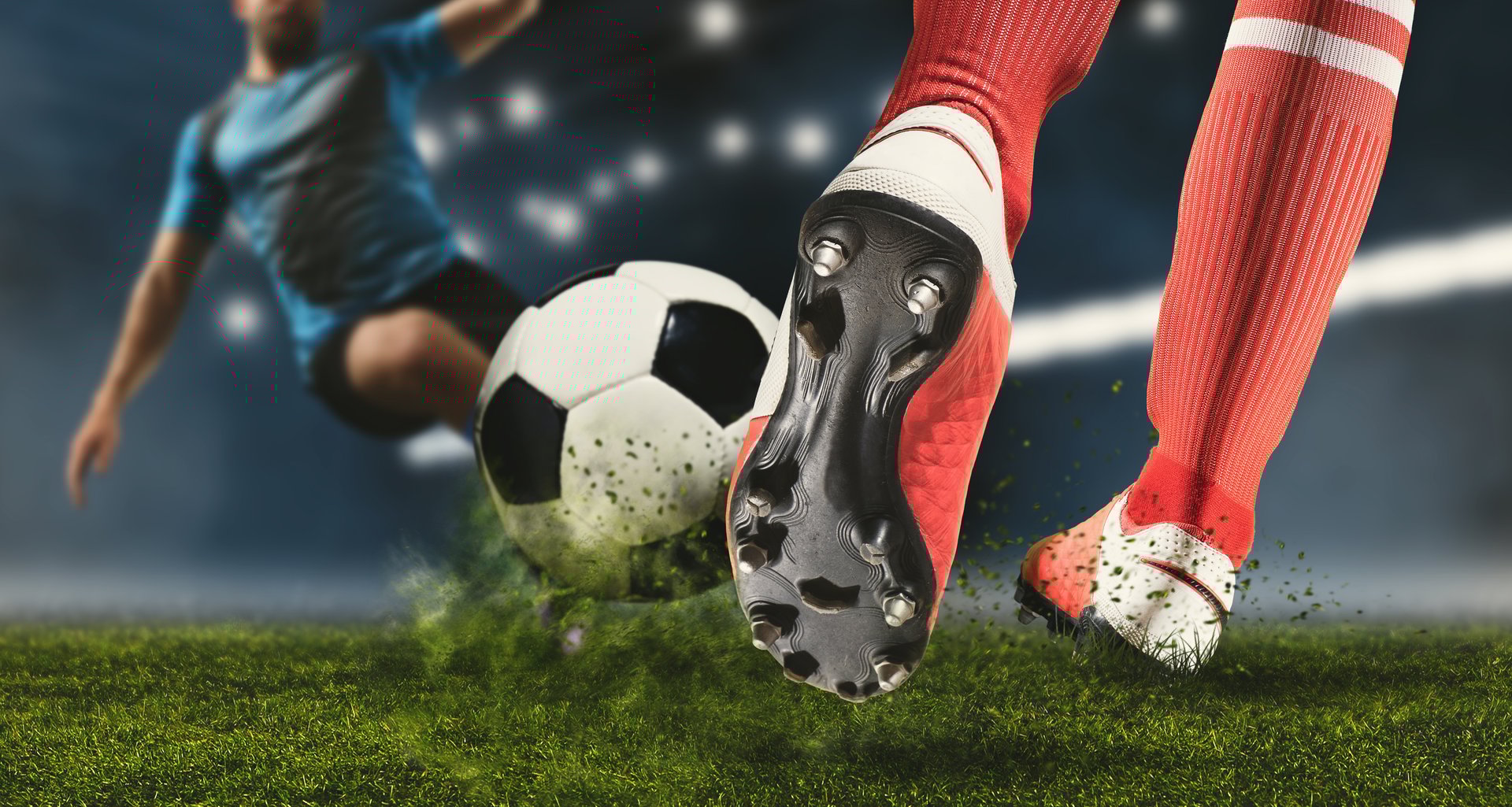 Football player man in action on dark arena background. Soccer player making sliding tackle