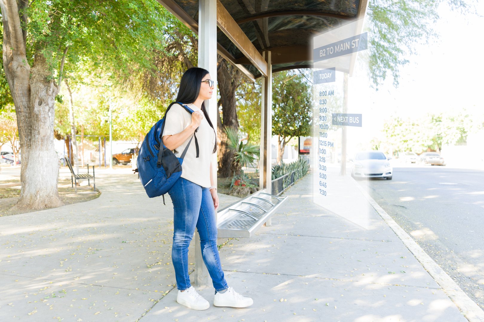 Latin student checking bus schedule at bus stop