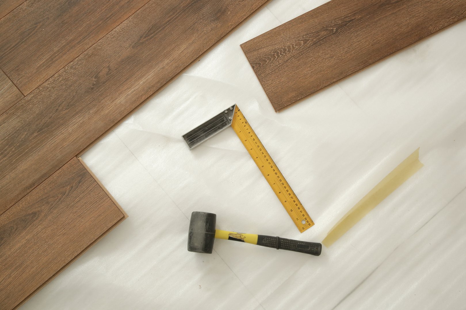 Rubber hammer, ruler with angle bar, tape meter, jig saw and other tools for installation of laminate vinyl floor. Home improvement, new floor installation.