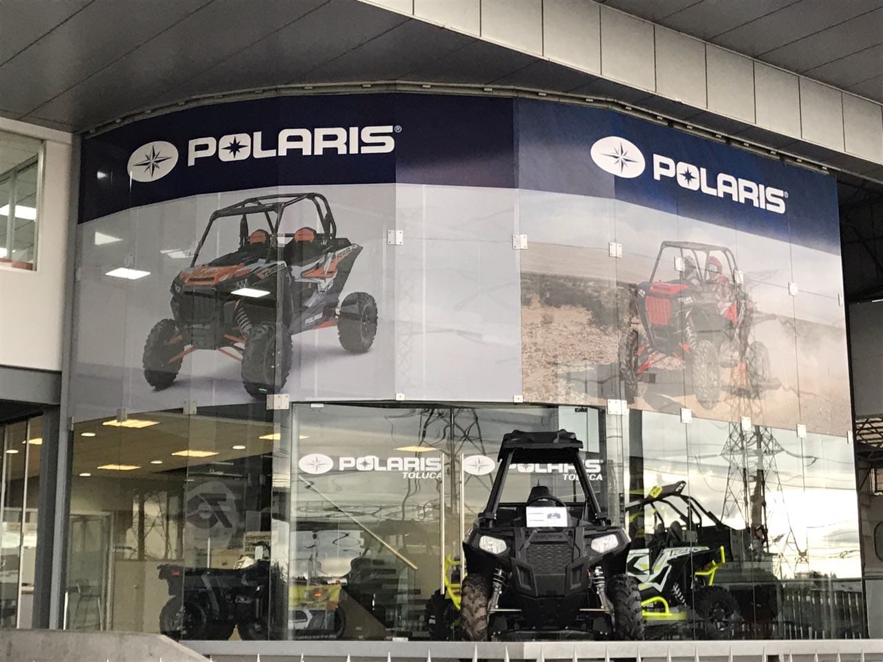 Polaris store exterior with large posters of off-road vehicles and ATVs displayed, showcasing various models.