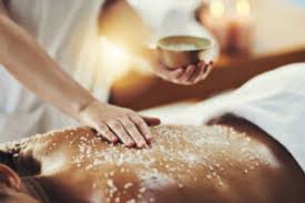Person receiving a relaxing back massage with a salt scrub, therapist applying the scrub in a spa setting.