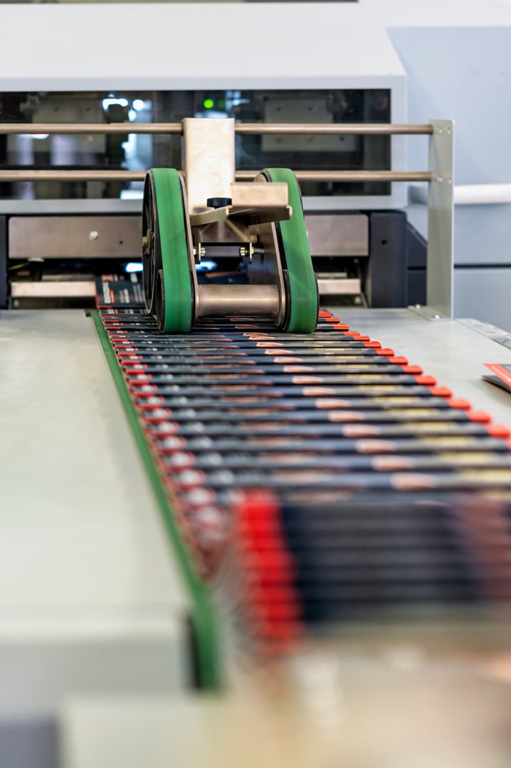 Industrial print finishing machine folding and sewing brochures in a print shop