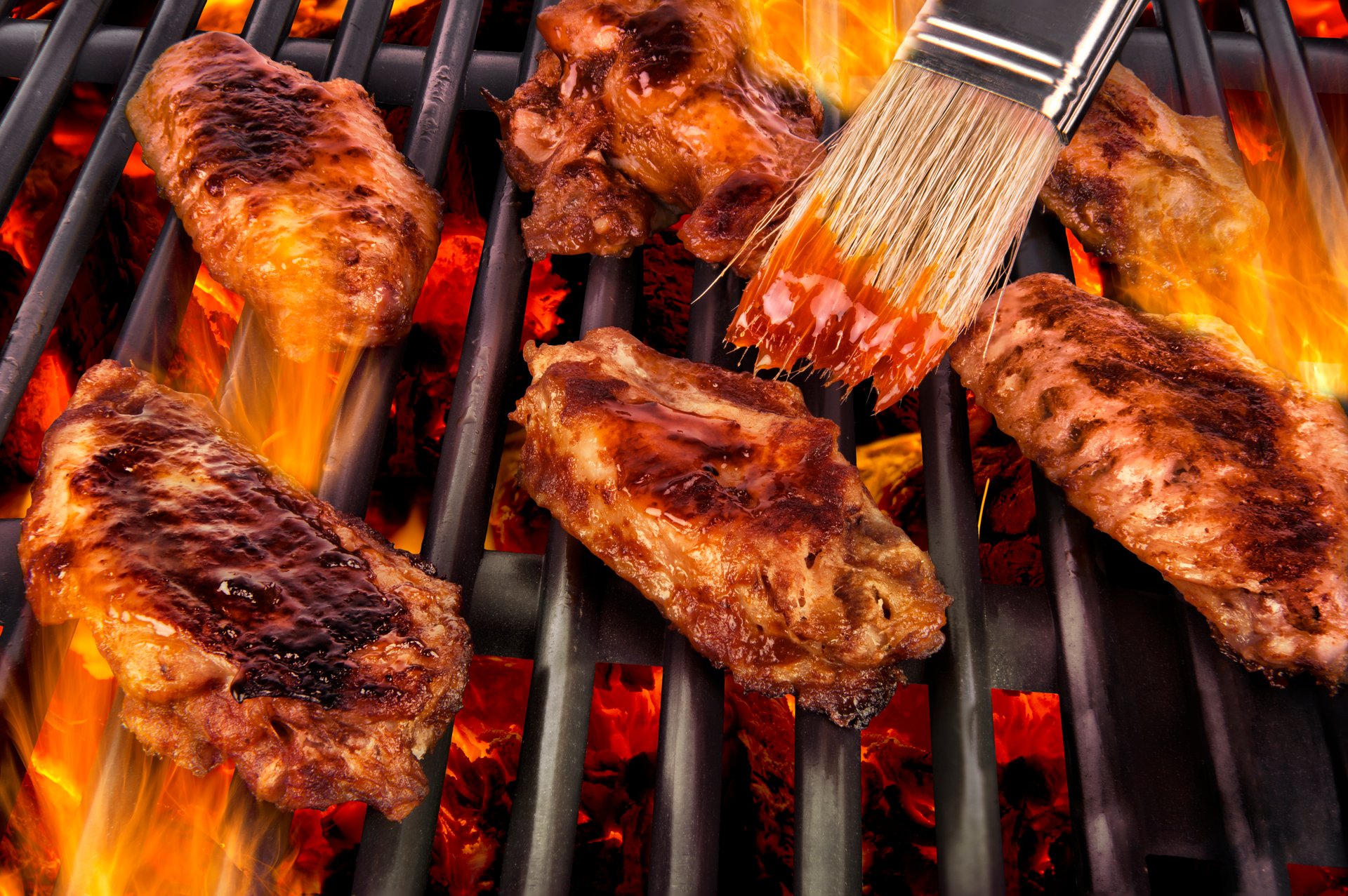 Fresh chicken wings cooking on barbecue grill.