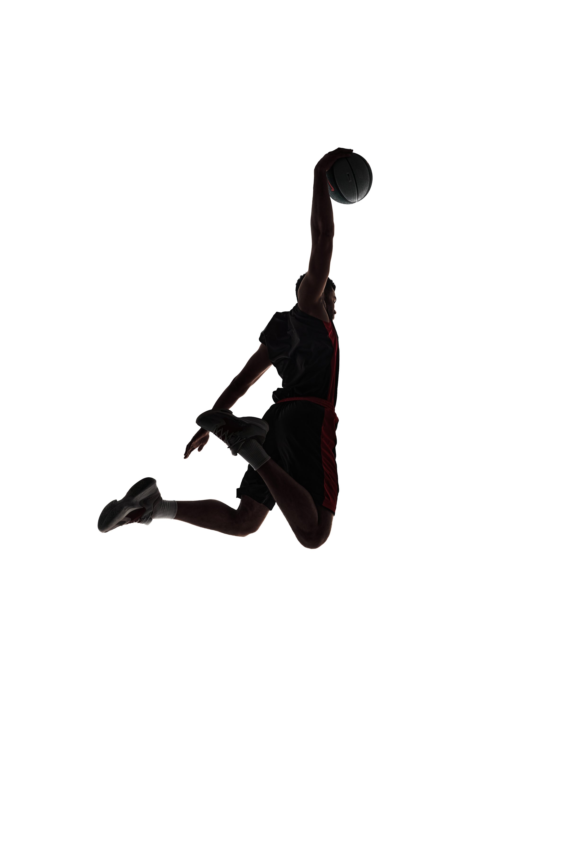 Slam dunk. Back view silhouette of young man, basketball player in motion throwing ball during game isolated on white background. Concept of professional sport, competition, game, tournament, action