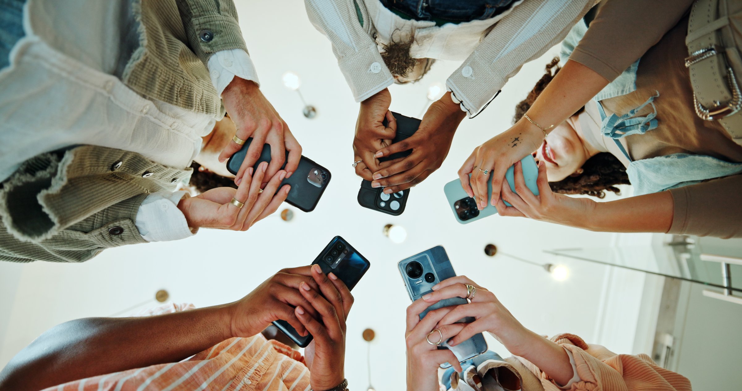 People, circle and phones for university registration, online and teamwork in education on campus. Students, low angle and huddle for project solidarity in college, collaboration and united learning
