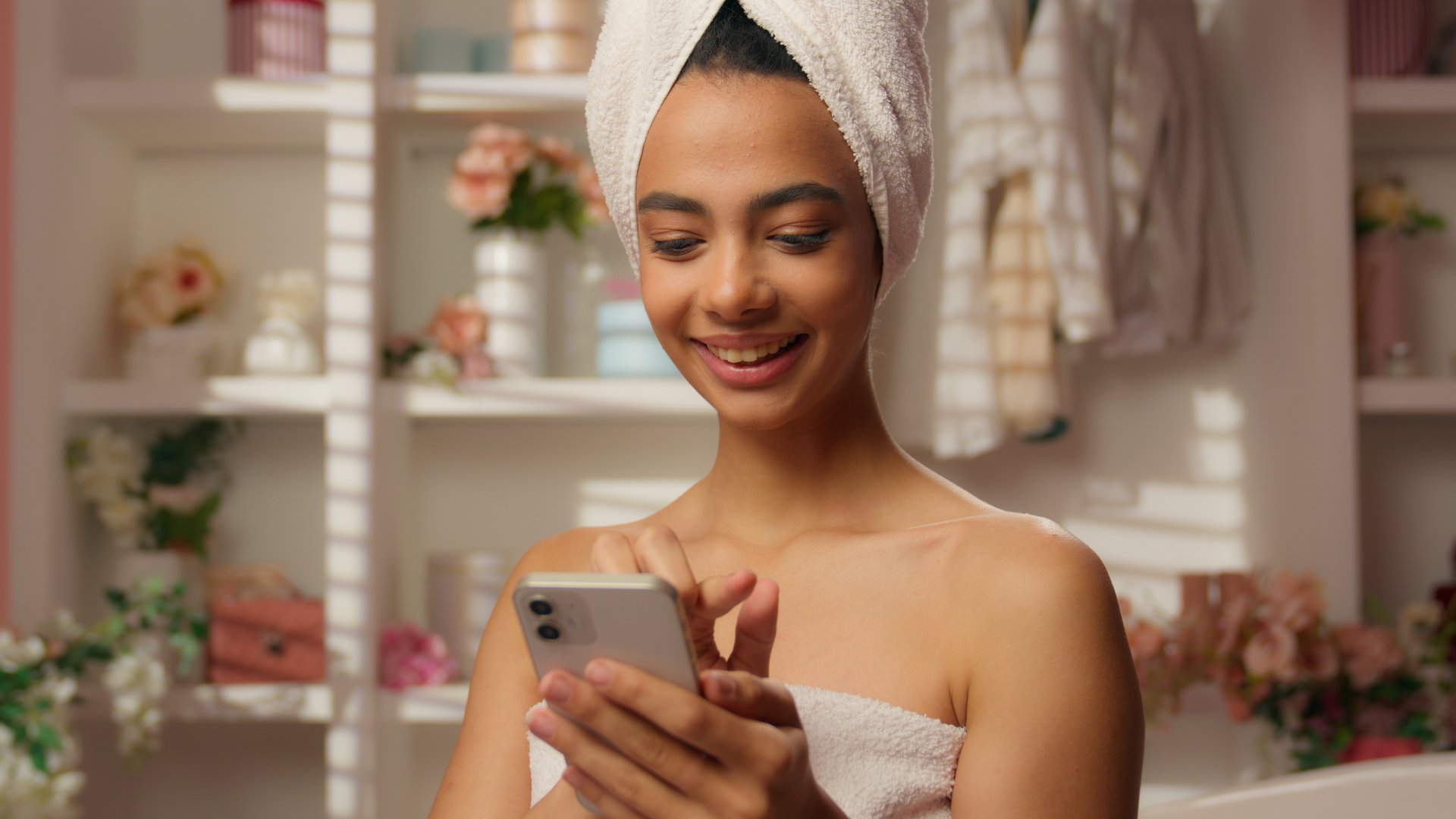 Hispanic beautiful woman in towel Arabian happy girl bathroom hotel smiling scrolling smartphone online shopping app cosmetics delivery home using mobile phone internet purchase beauty skincare bath. High quality 4k footage