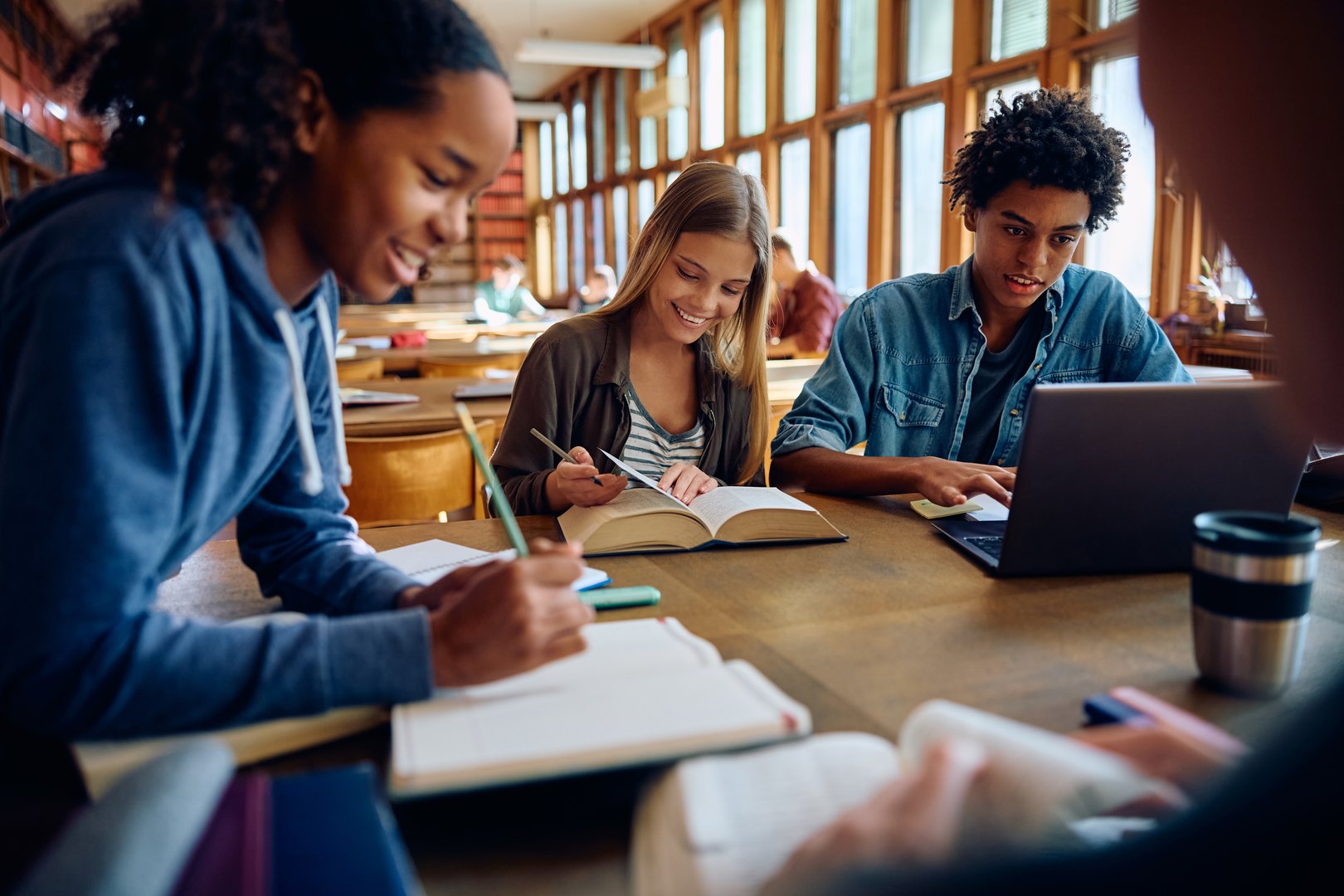 Group of happy classmates studying together at high school library.