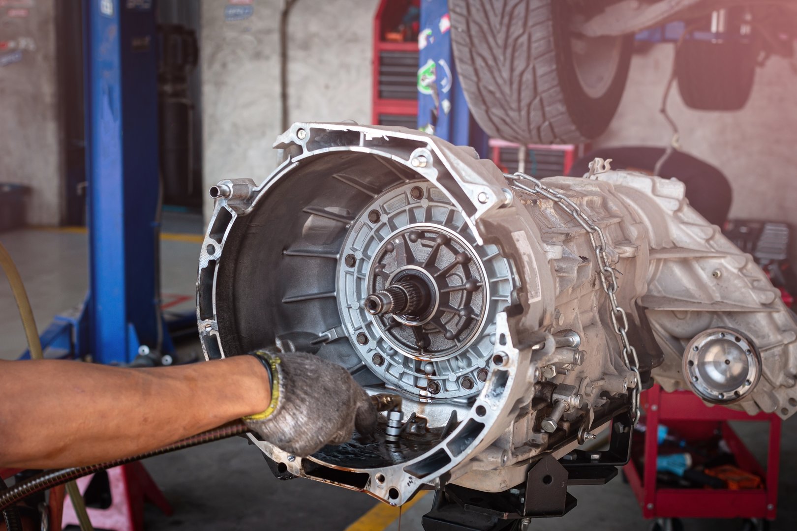 Auto mechanic working on car automatic transmission in auto repair shop.