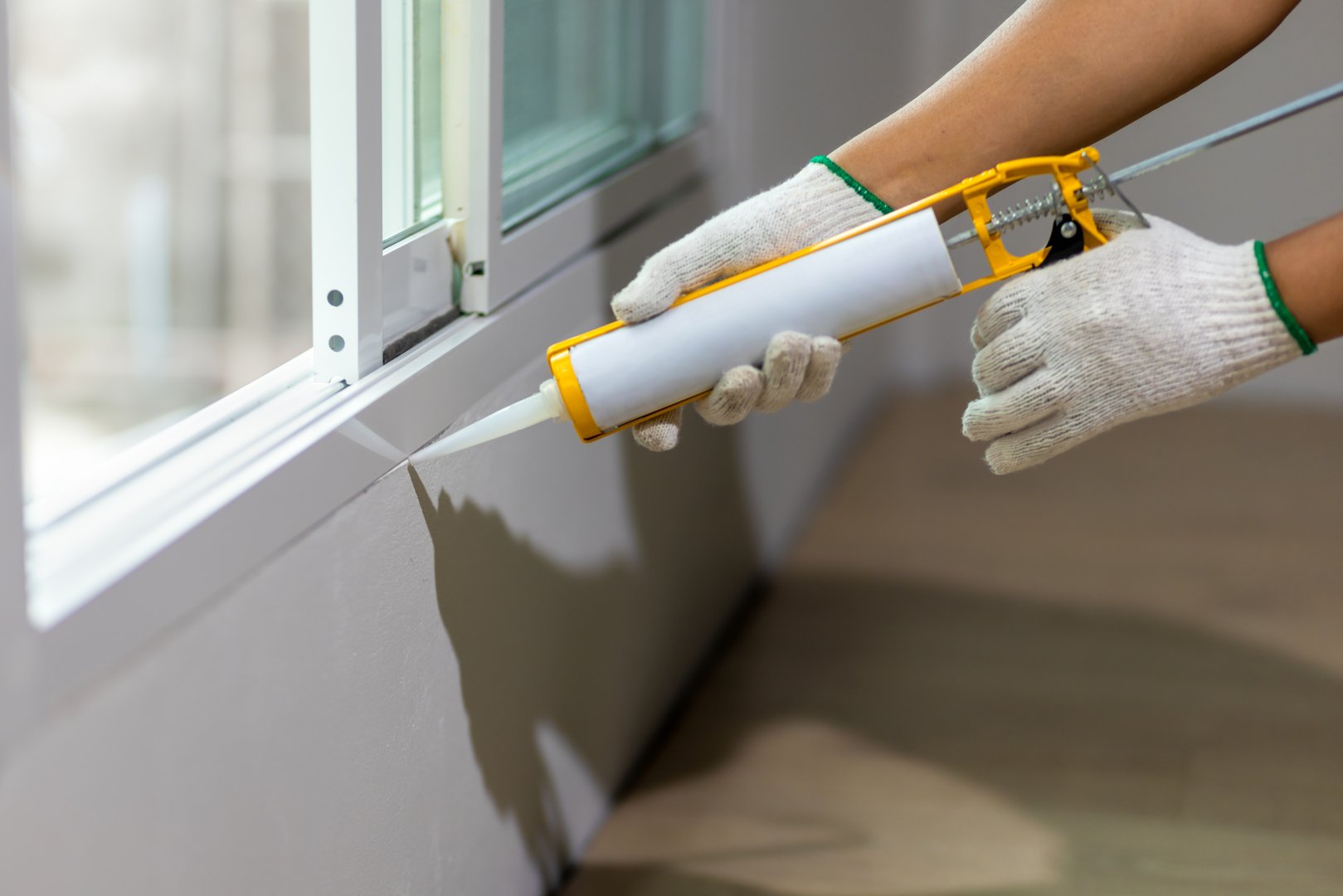 Construction worker using silicone sealant caulk the outside window frame.