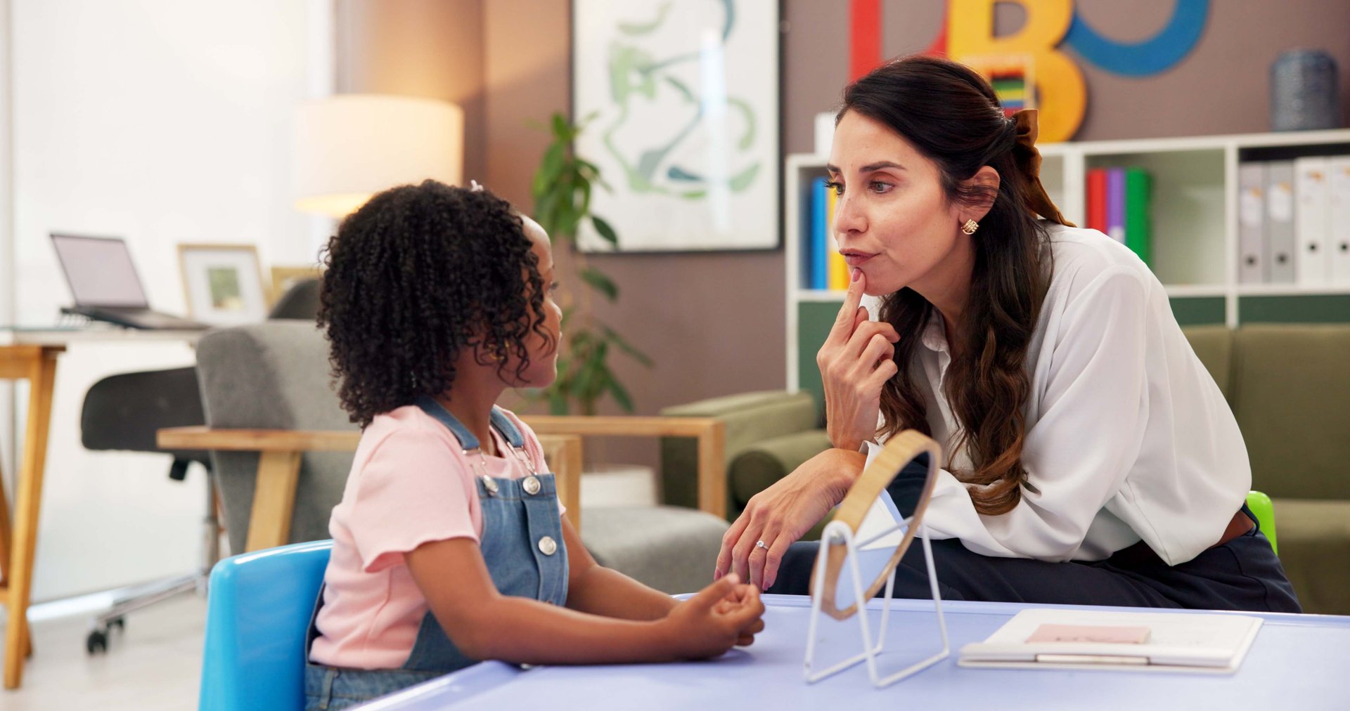 Mirror, speech therapy and help with woman and girl for language assessment, sound and teaching. Tongue placement, child development and phonics exam with person and kid for education consulting