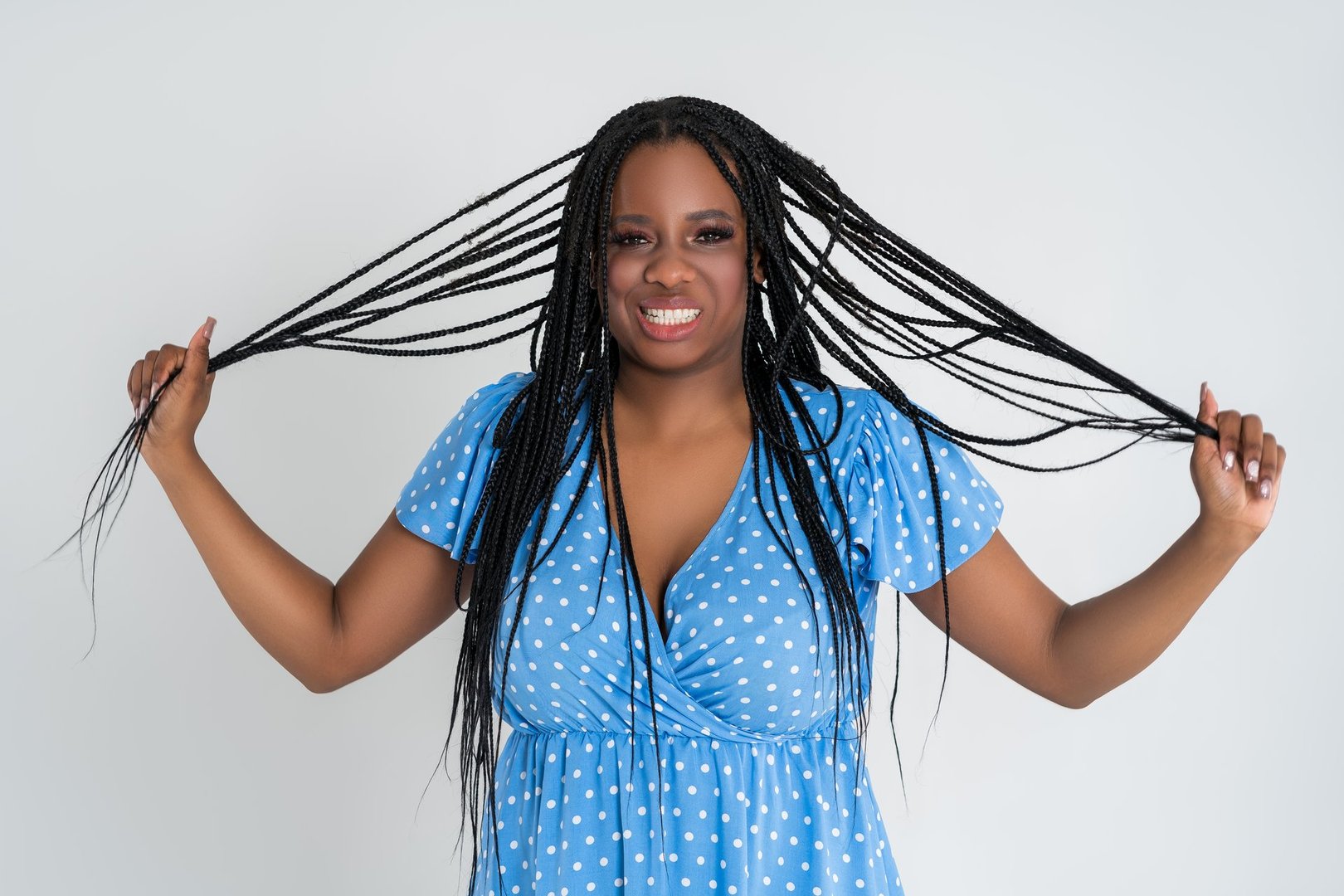 Happy plus size black model in blue dress, beautiful African woman with curvy figure and pigtailed hairstyle, afro braids