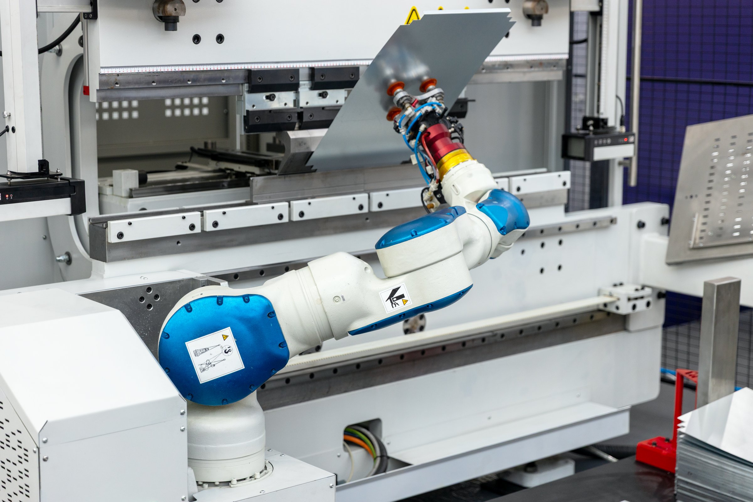 Close-up of collaborative robotic arm manipulating metal sheet in high-tech automated factory environment