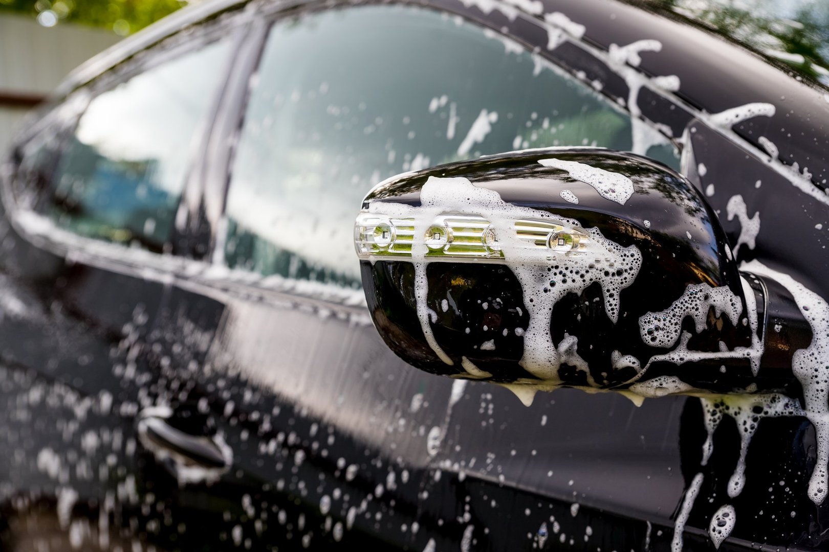 Outdoor car wash. Gentle Car Washing. Modern Compact Car Covered by Water.