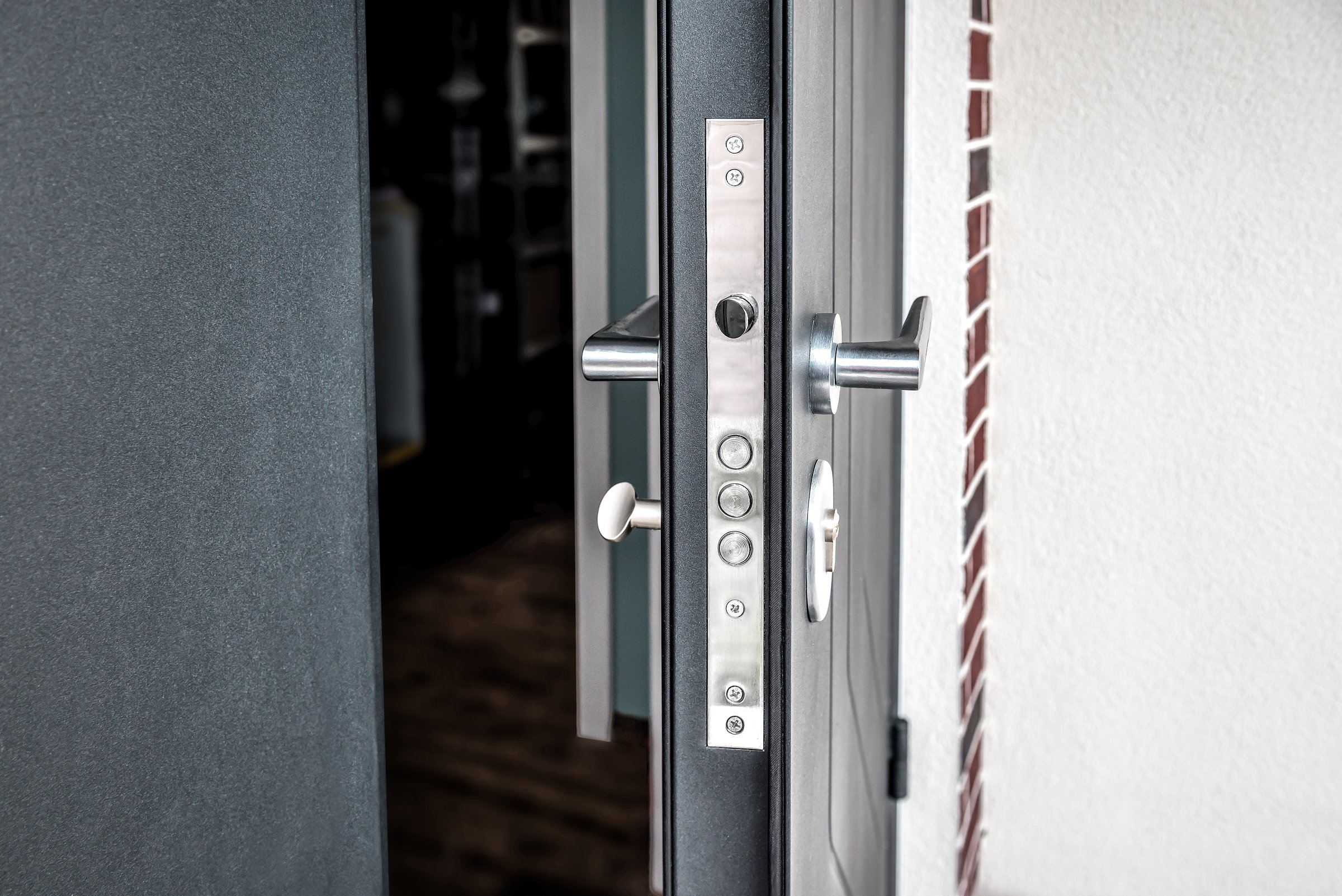 New steel three bolt door lock installed on the front door of a new build house. Industrial theme