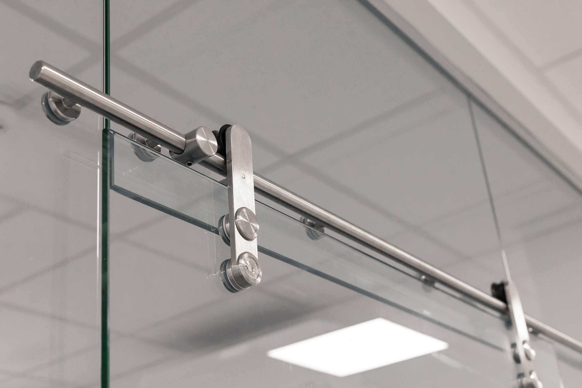 Close-up view of sleek glass sliding door hardware showcasing a stainless steel track system. This setup enhances the modern aesthetic of the interior space, emphasizing functionality.