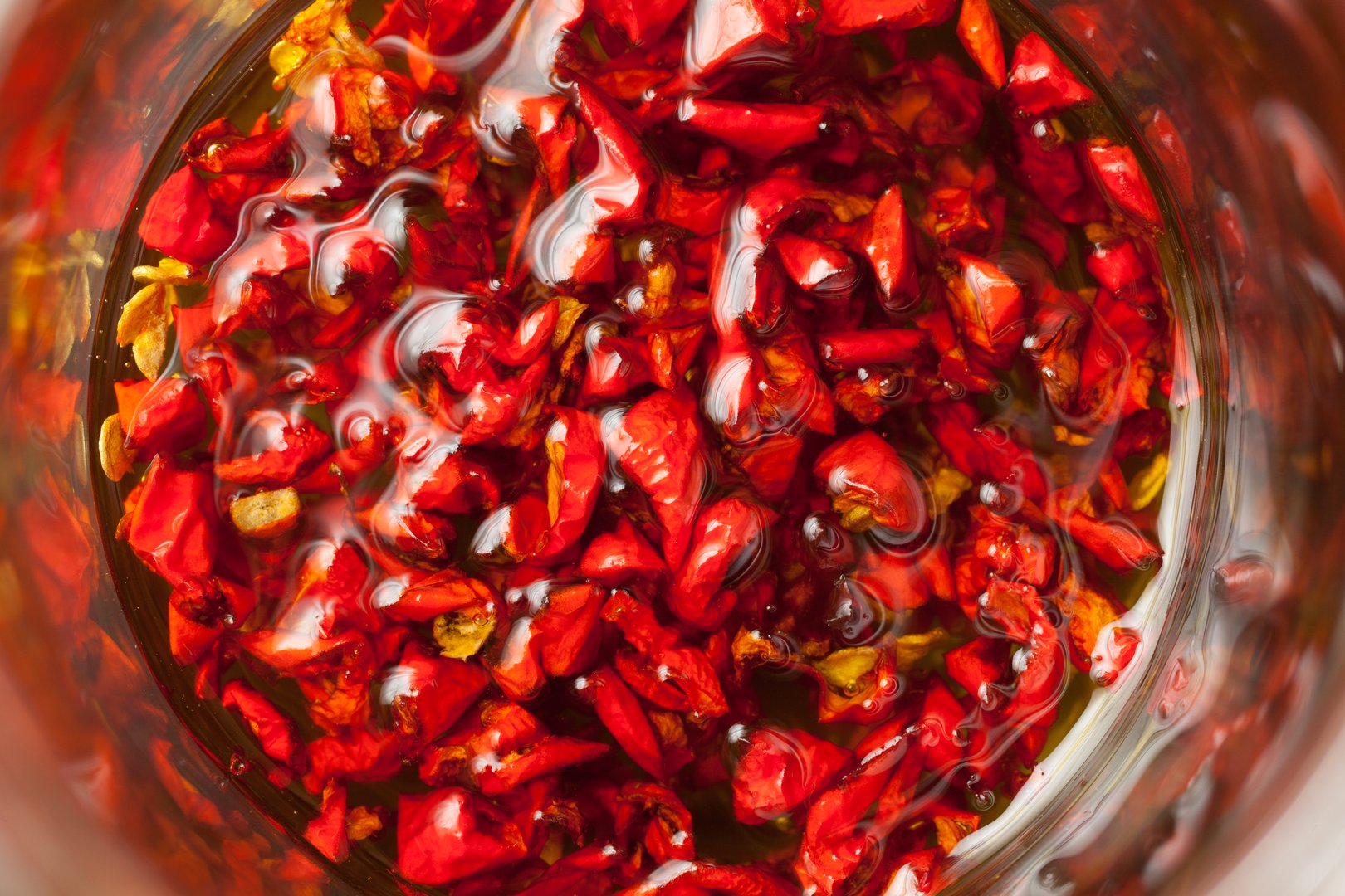 Red hot Trinidad moruga scorpion peppers chopped in olive oil on black background