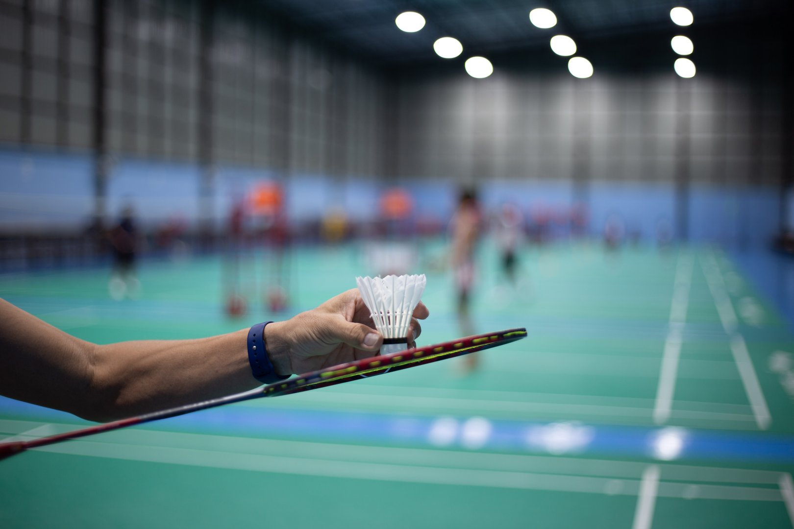 Athlete's hand holding a badminton shuttlecock in the competition field