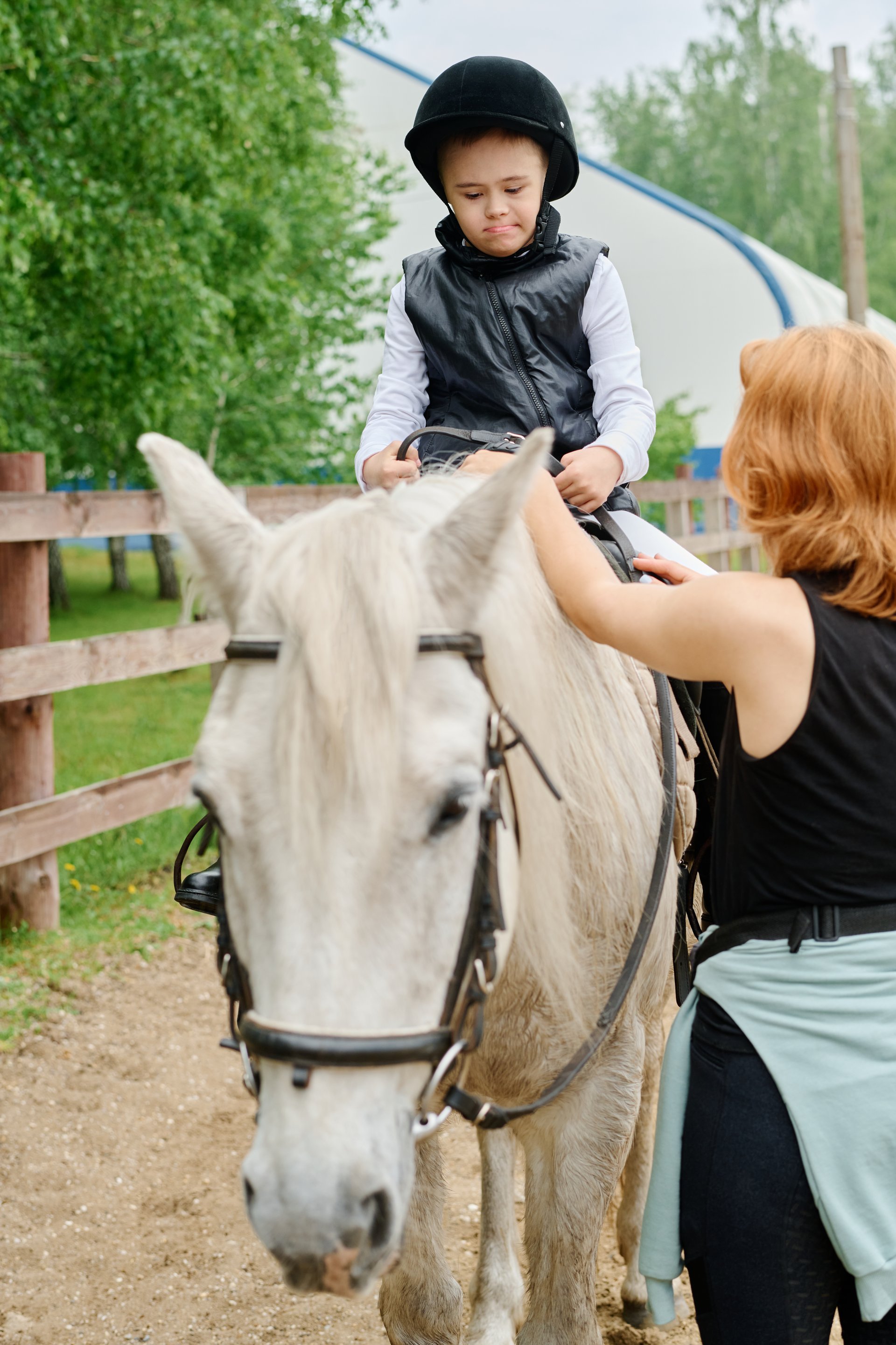 Kind met helm en veiligheidsvest op wit paard