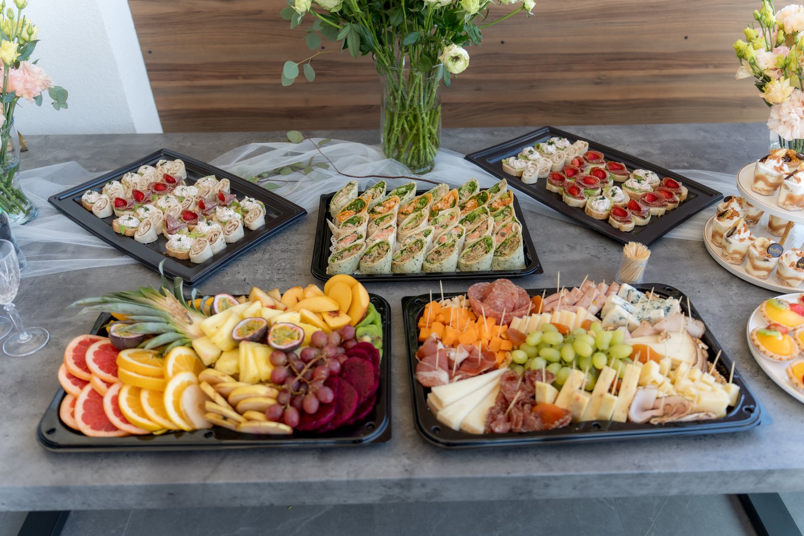 Guests enjoy a vibrant display of colorful fruits, bite-sized savory appetizers, and desserts at a special celebration