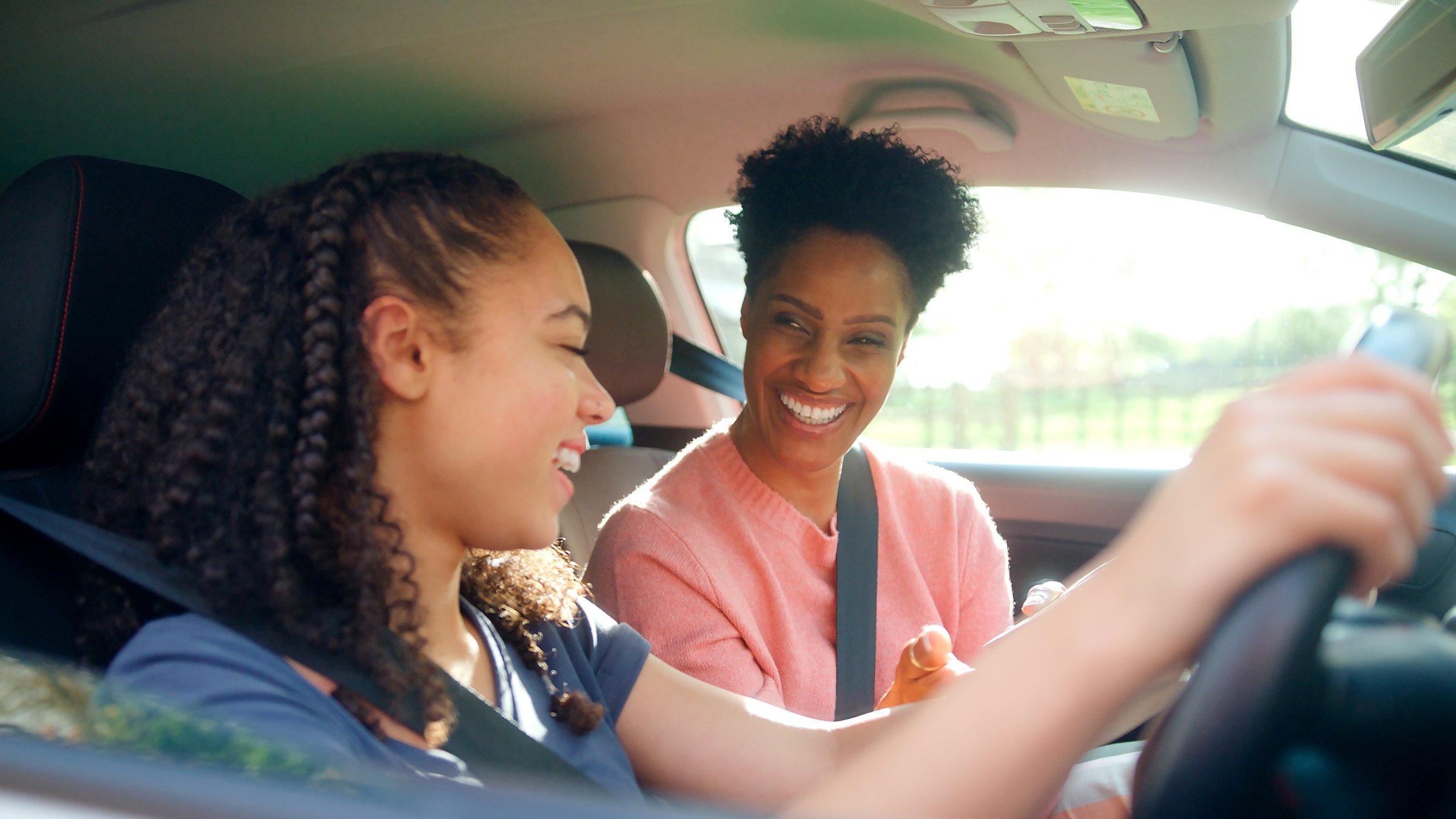 Teenage Girl In Car Having Driving Lesson From Female Instructor Or Parent
