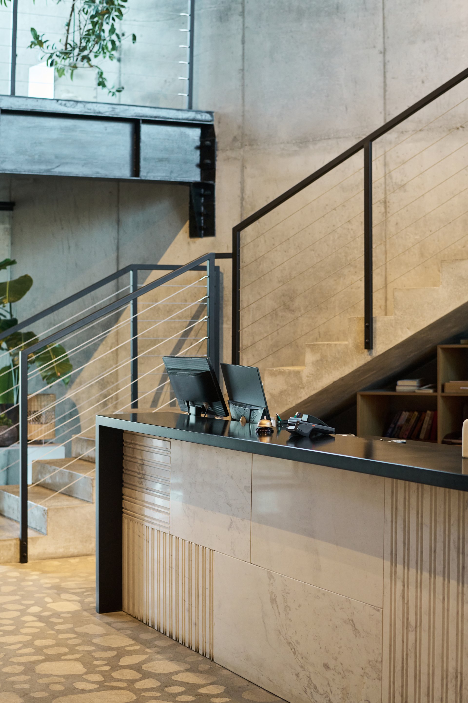 Modern office reception area featuring minimalist design with clean lines, concrete walls, and a sleek staircase creating a sophisticated atmosphere