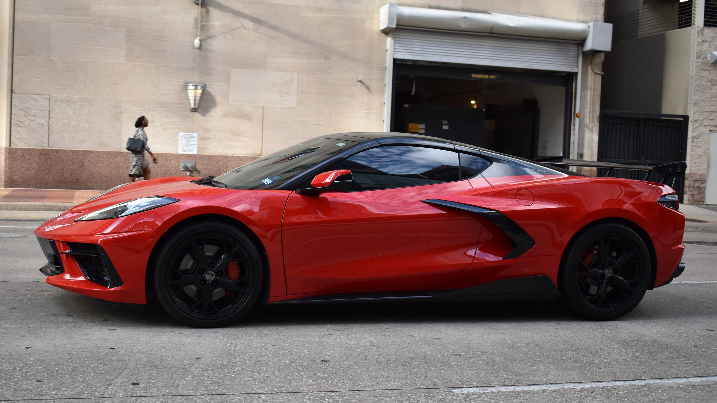 Houston, TX USA 10-4-2024 - A portrait of a red and black Chevy Corvette C8 3LT sports car traveling near the McKenney Parking Garage in the downtown financial district of Houston.