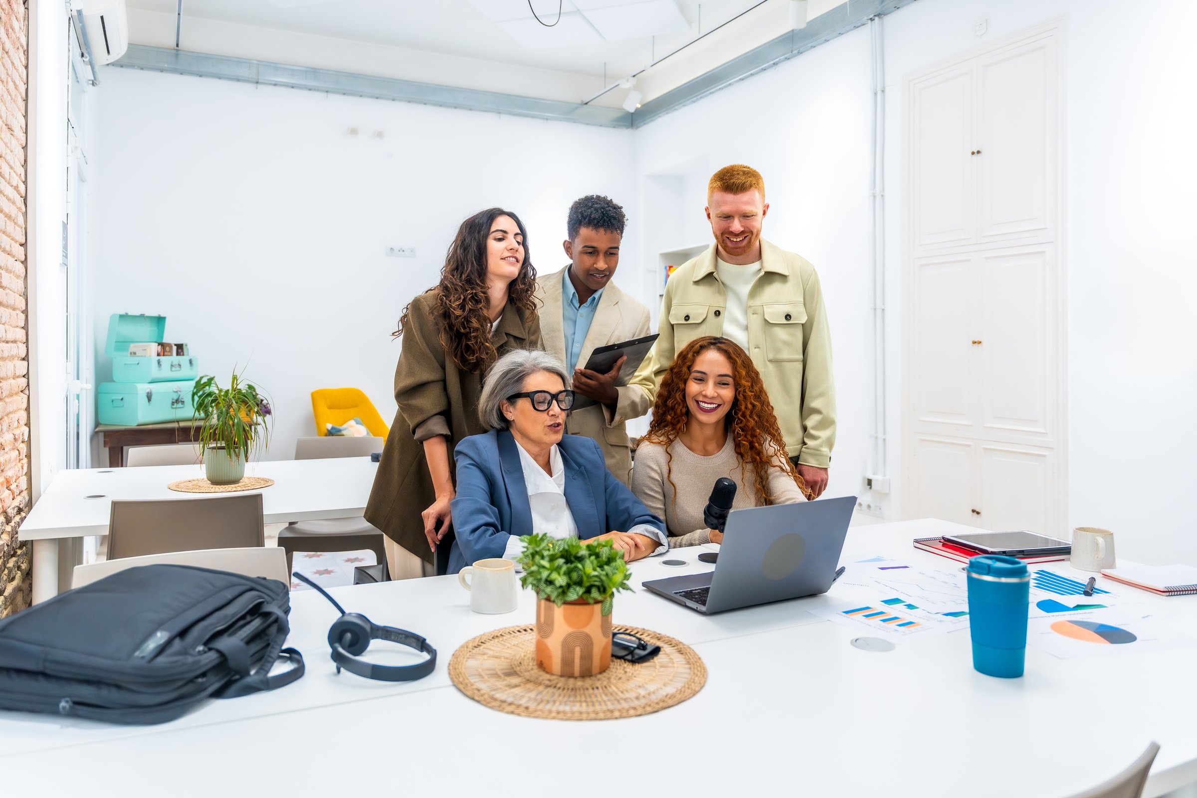 Diverse business professionals working together, discussing ideas, and recording a podcast in a modern office space, showcasing teamwork and innovation
