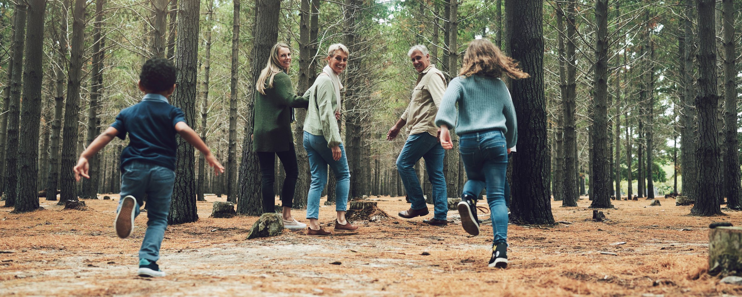Forest, big family and adventure with children, parents and grandparents walking in nature for outdoor hiking, fun and trees on wellness vacation. Running kids, travel and happy man and women in woods