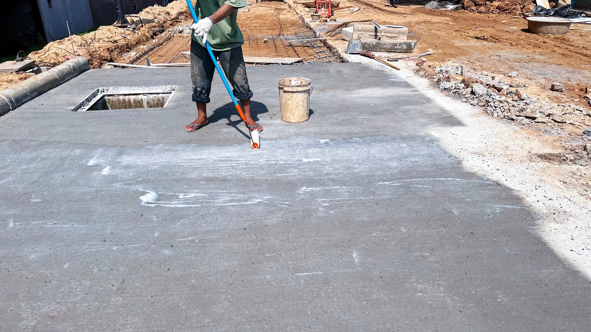 Technician applies concrete curing agent to prevent cracking. concrete primer Steps for applying foundation with a roller on concrete floors Primer for strengthening the surface.