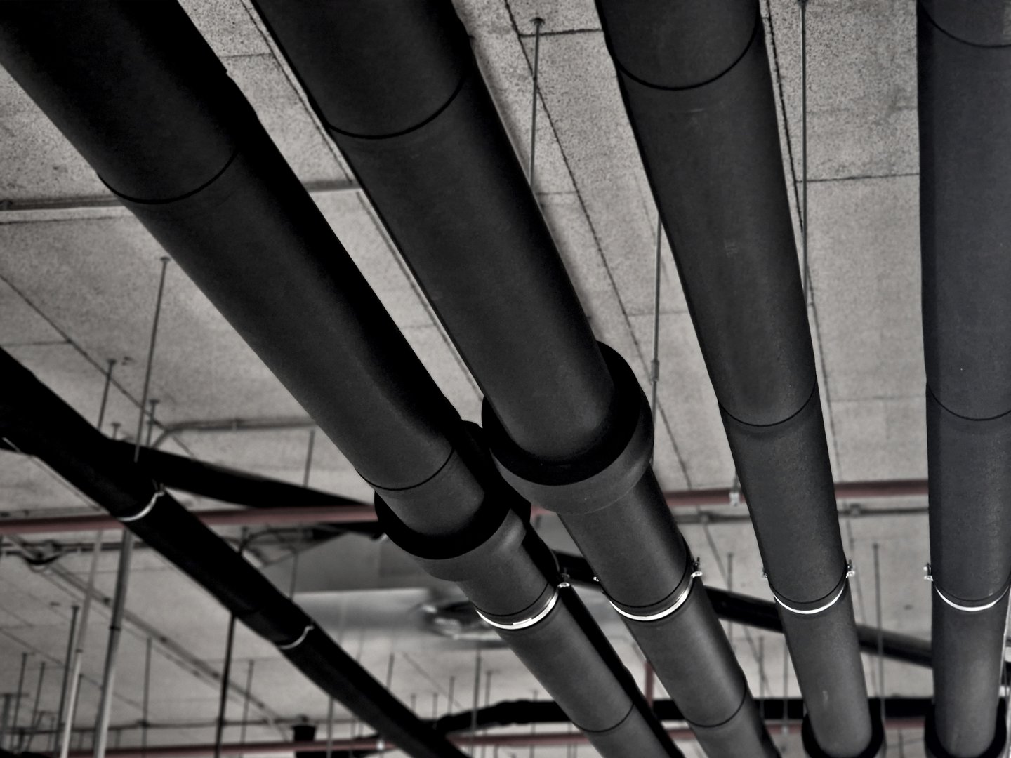 Insulating polyethylene cover for pipe insulation. suspended pipes on holders and handles. pipes from heat pumps and hot water exchangers are isolated in the underground garage