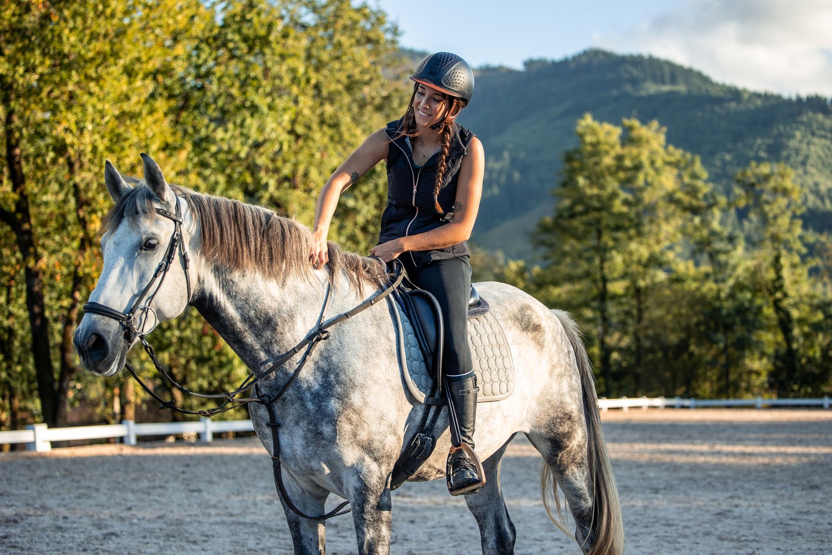 smiling young woman rider shows her love and affection for her horse after a productive equestrian class. With gentle strokes and a warm expression, she reinforces the bond between them