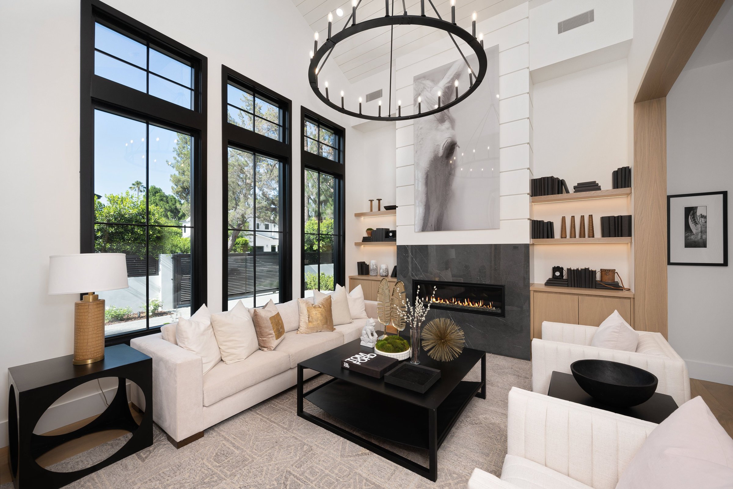 Modern living room with high ceilings, large windows, a fireplace, and stylish decor in a contemporary home.