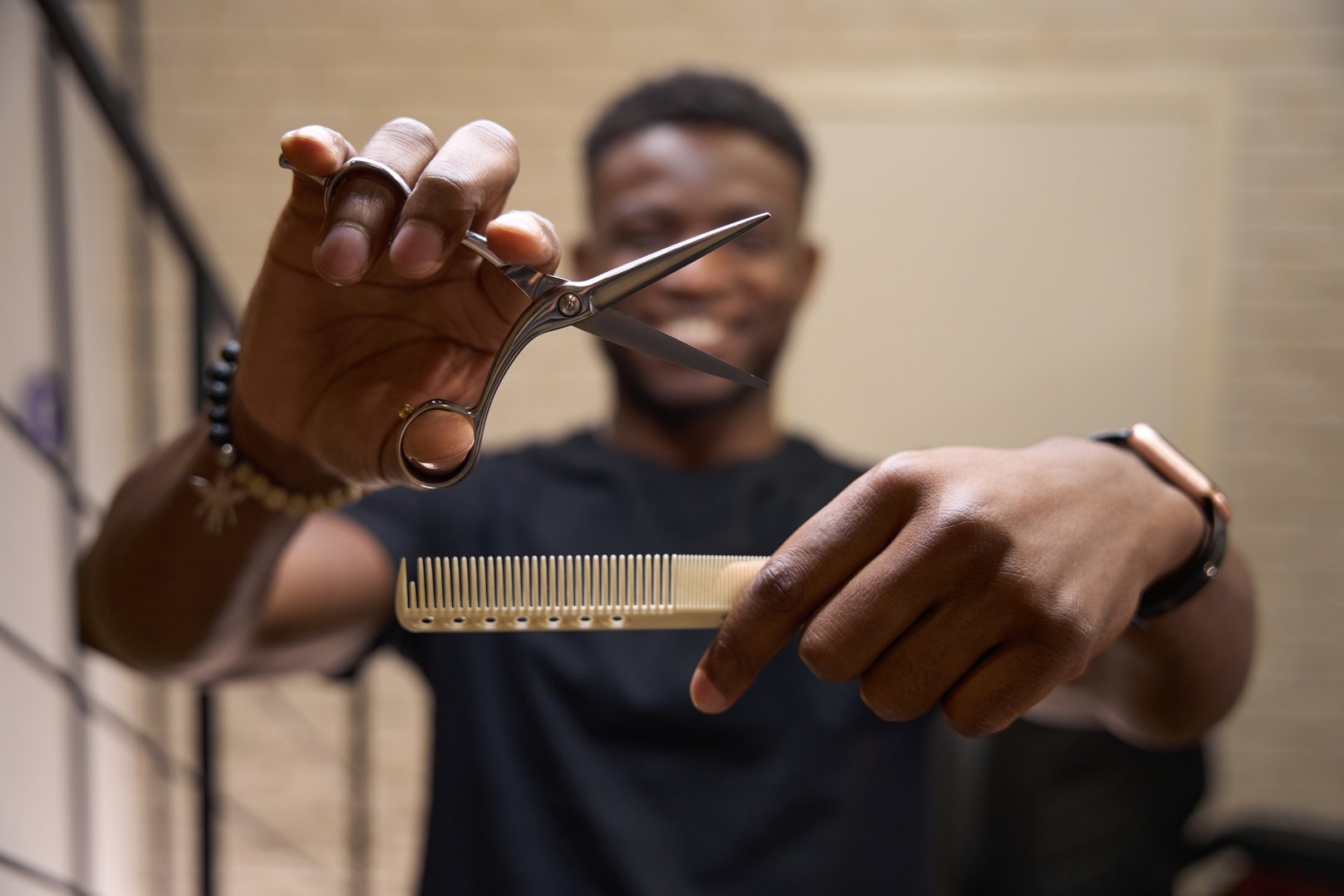 Hairdresser holds a working tool in his hands, the master has curly hair