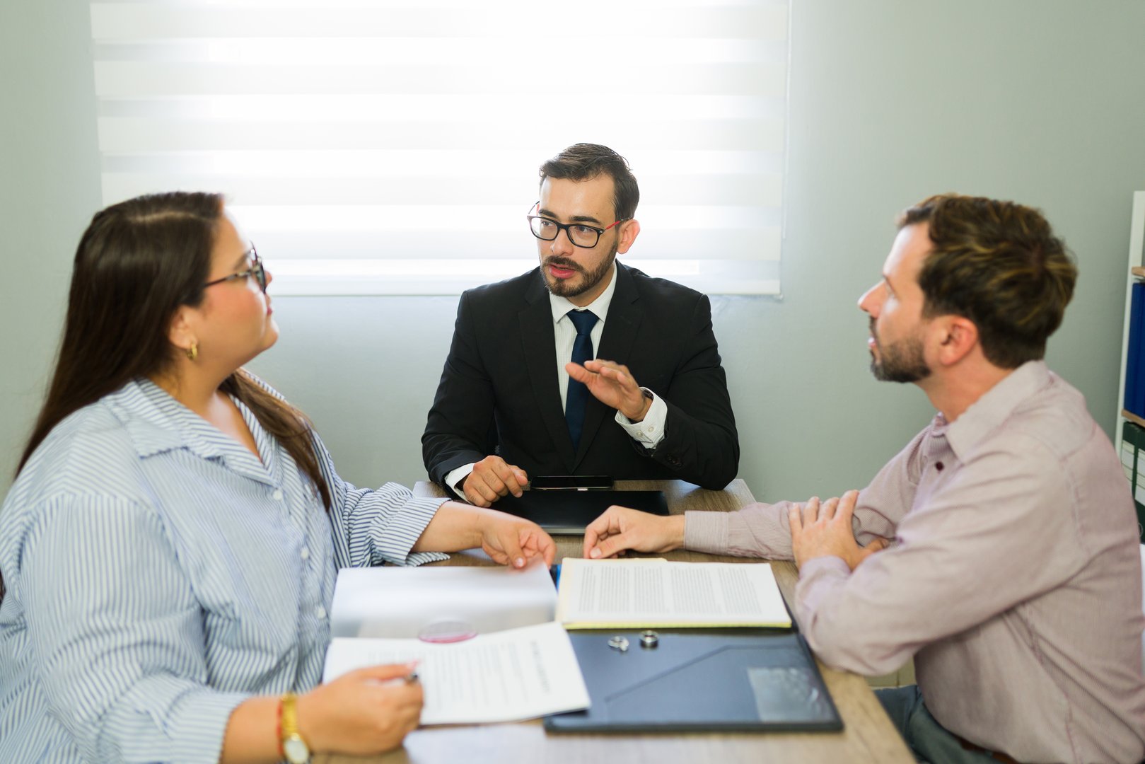 Attentive lawyer mediating a discussion between a man and a woman about their separation and legal agreements