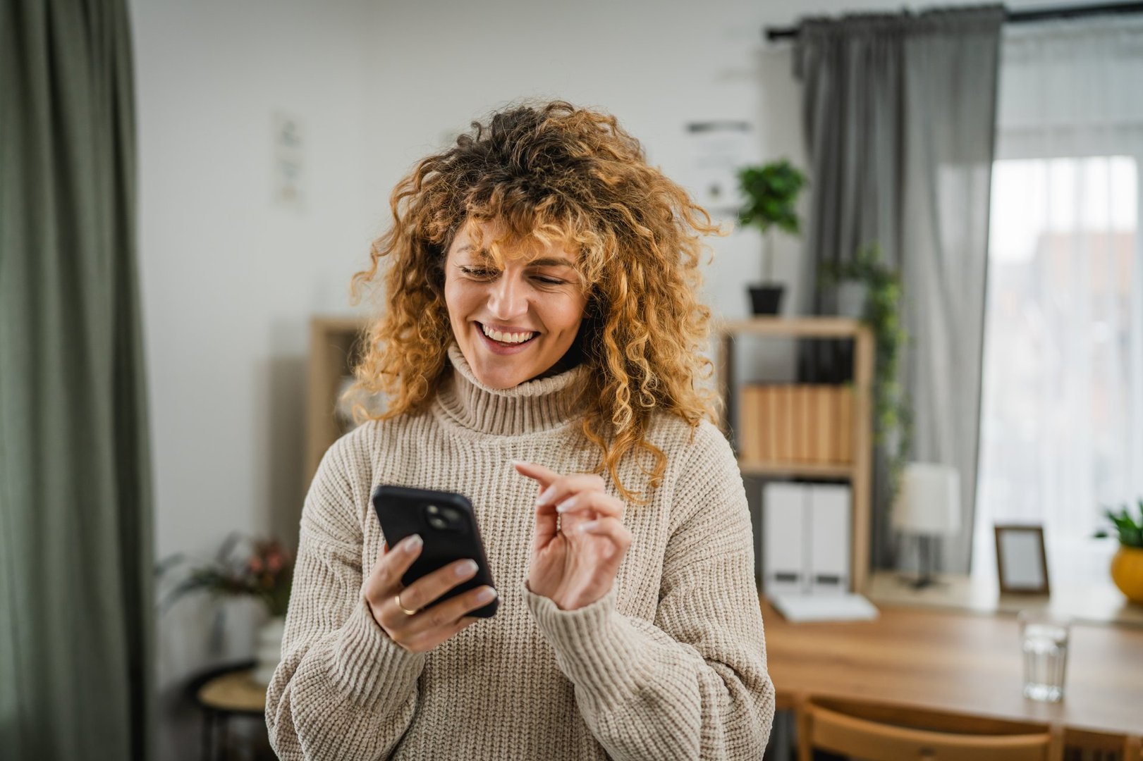 excited adult woman use mobile phone for fun at home