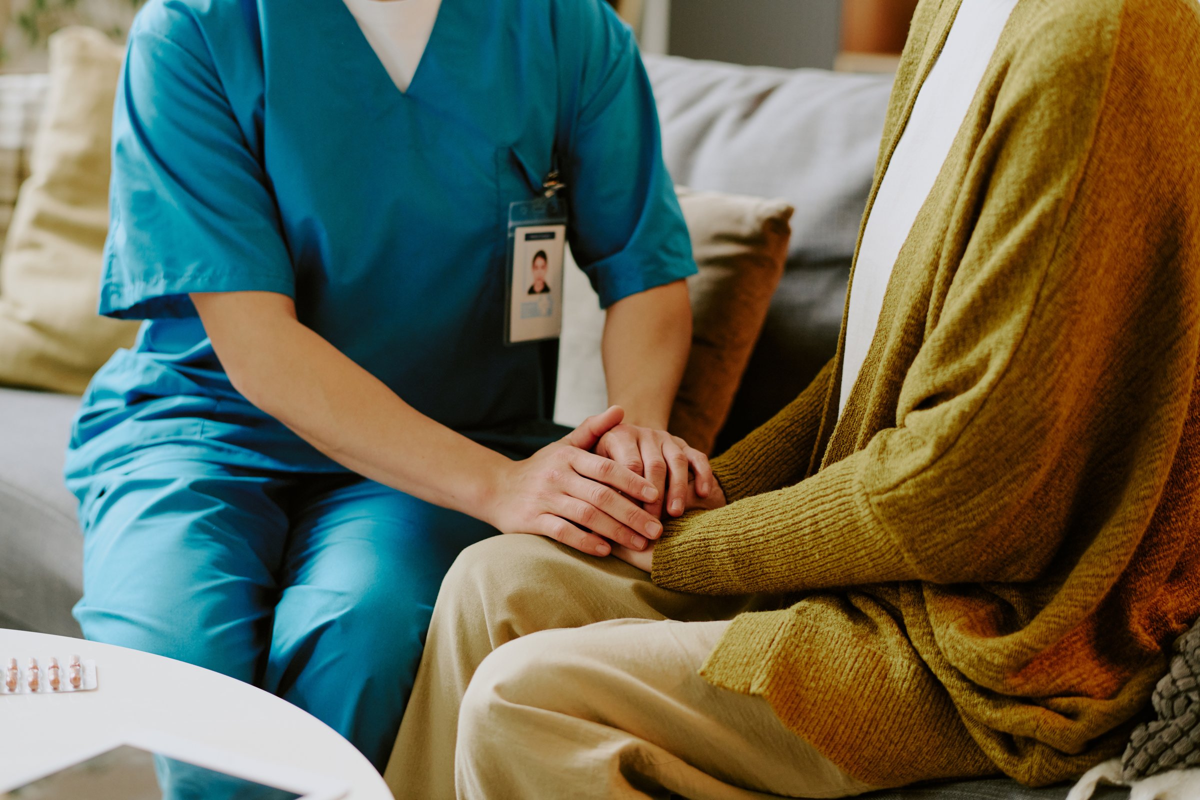 Medical professional holding hands with an elderly person during a consultation, offering comfort and support in caregiving setting