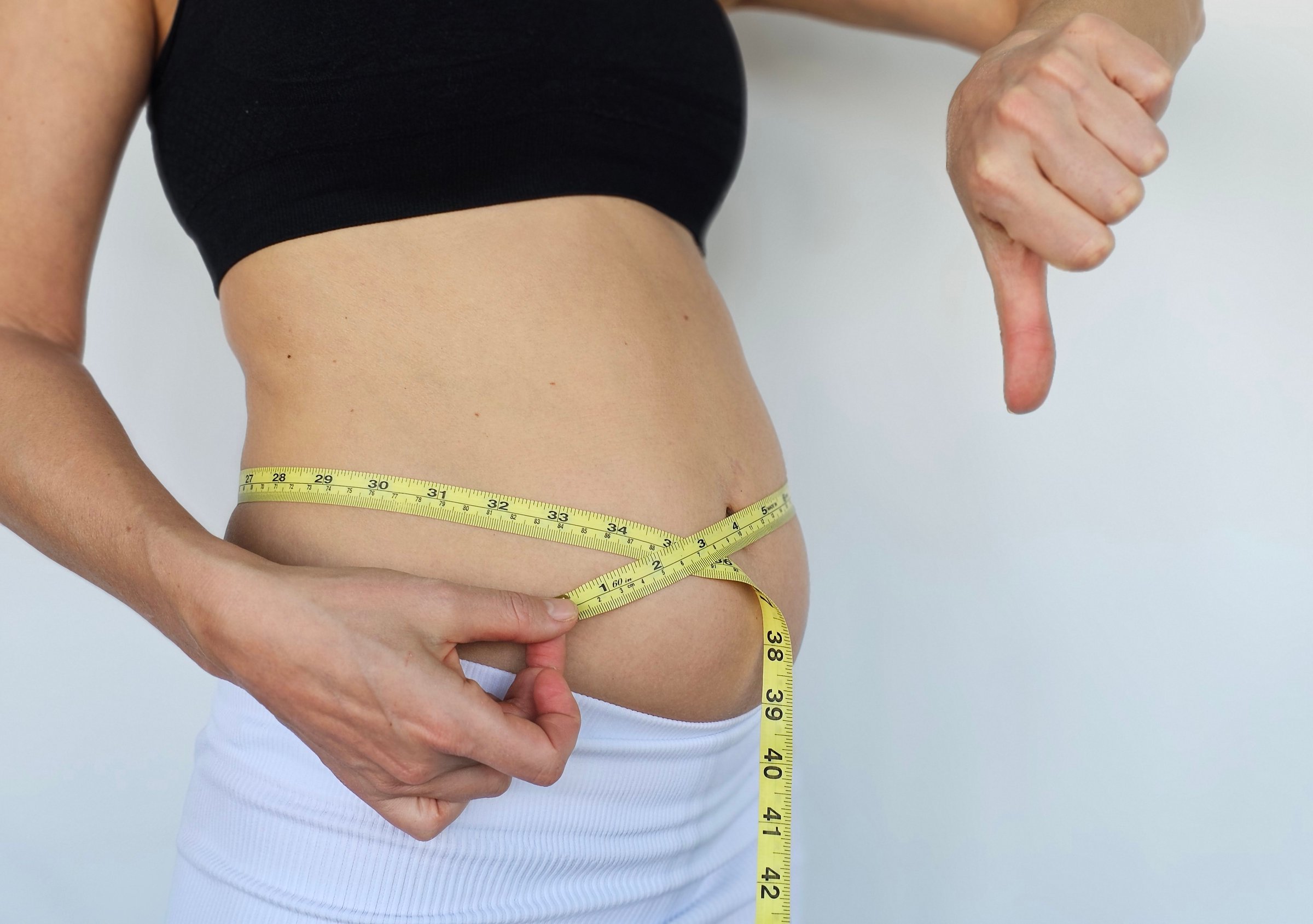 woman measures her waist with a tape and shows a bad result. Weight loss, fighting excess weight and obesity. Comparison of parameters before and after.