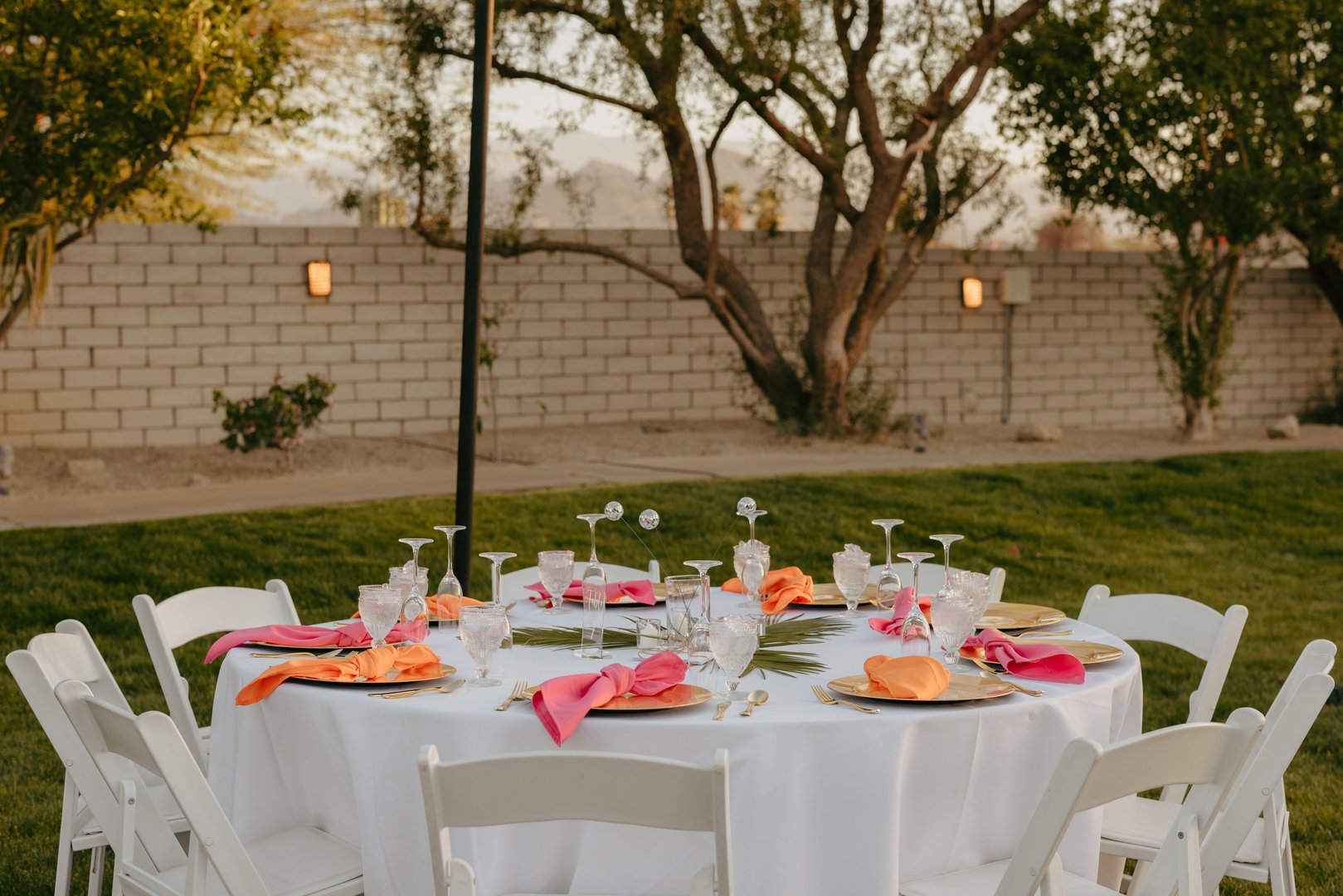 A wedding table decorated with red and orange accents and a white tablecloth