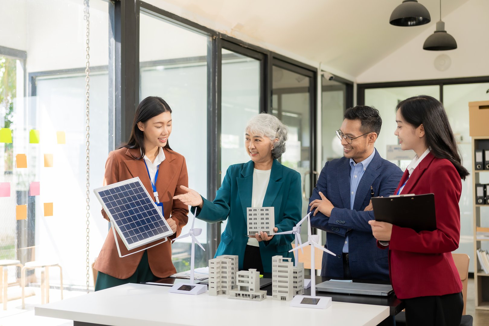 Team of engineers in factory office, presentation on ESG project planning, solar panels, wind turbine power generation, sustainable energy efficiency.