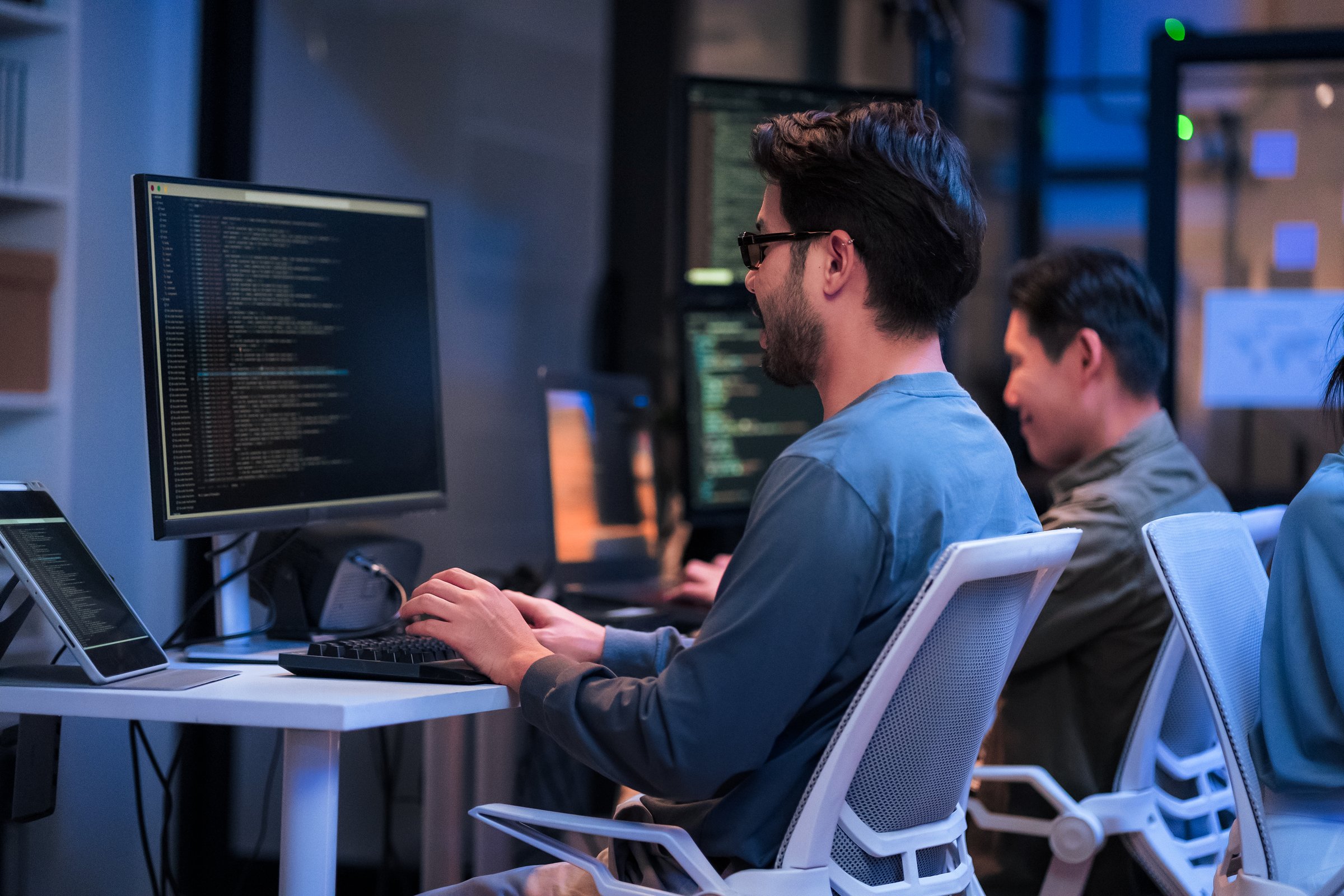 young Asian software development manager leads a late-night office discussion with his executive team, mentoring developers and analyzing source code to guide programming and project development