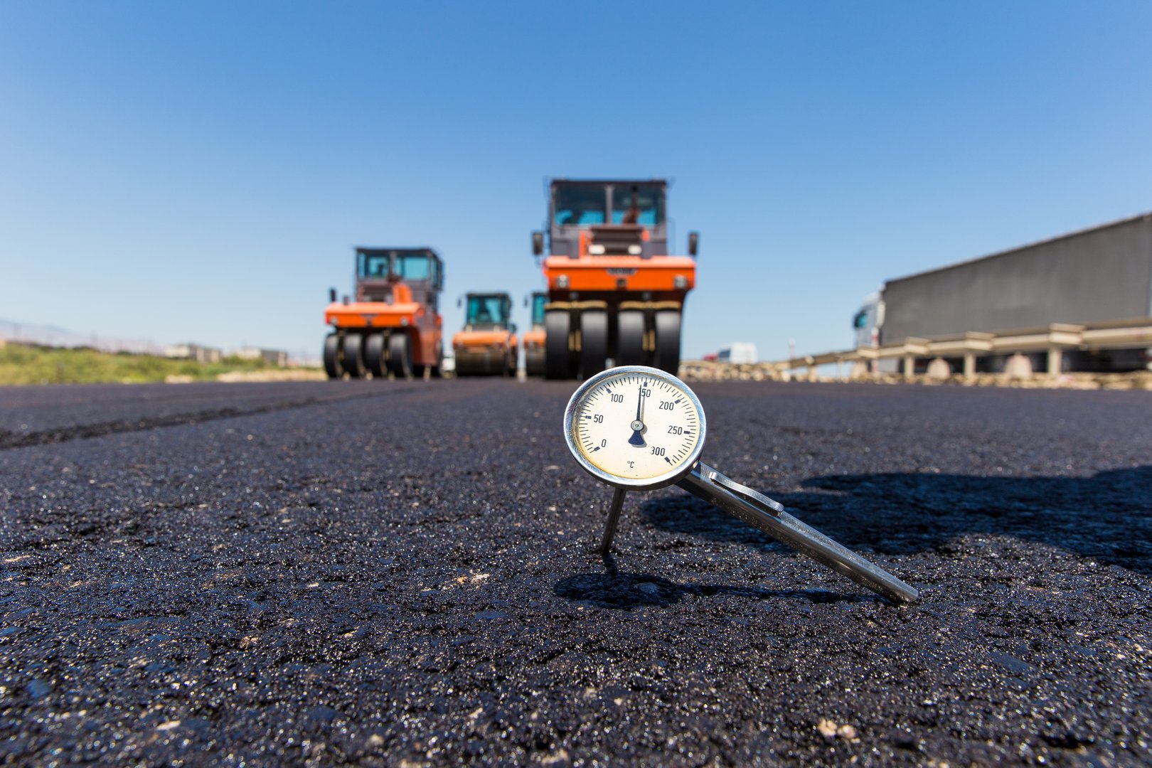 Thermometer measuring temperature in hot asphalt on road construction site