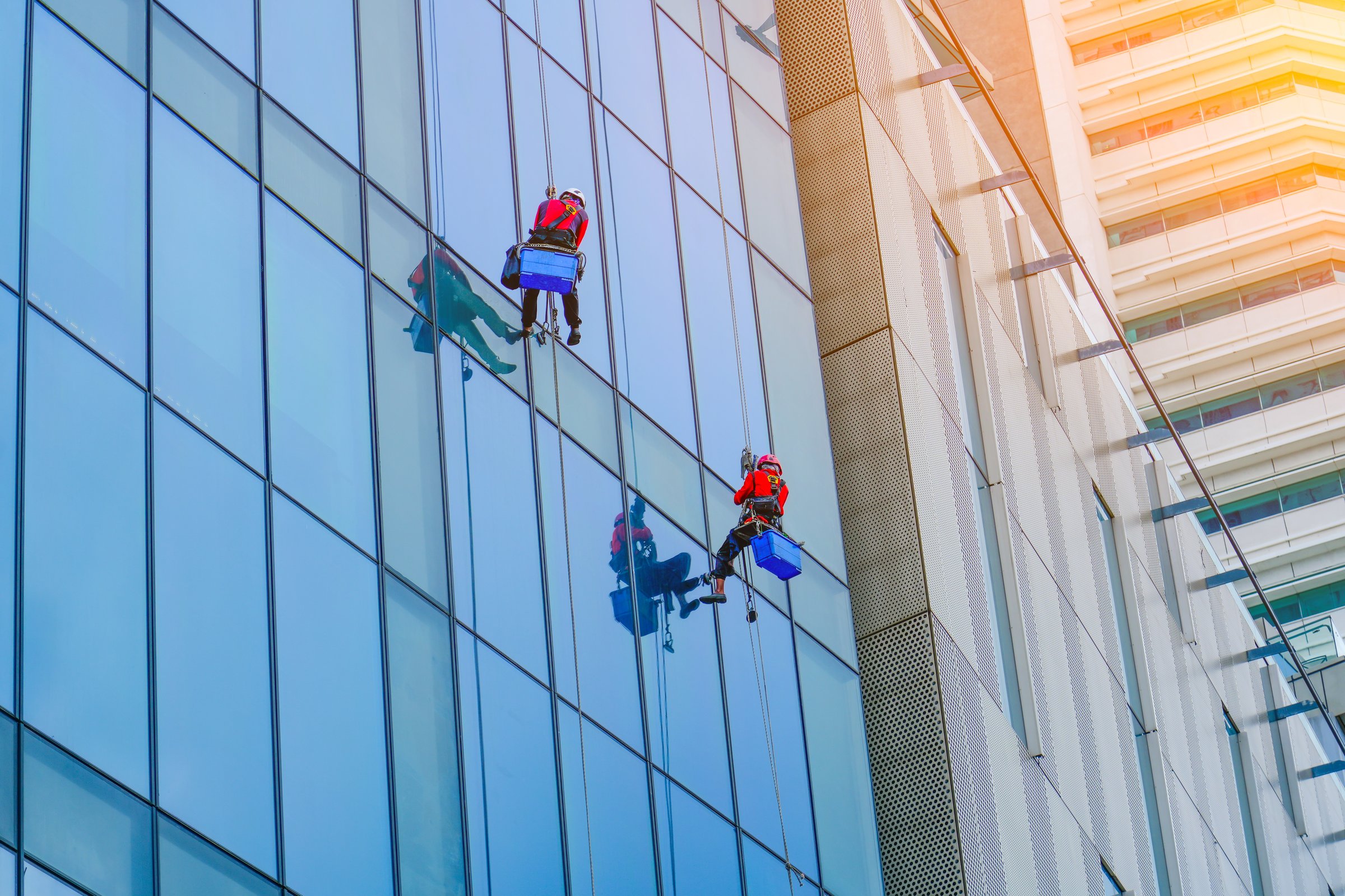 Work on the heights. Industrial mountaineering, group of workers cleaning windows service on high rise building
