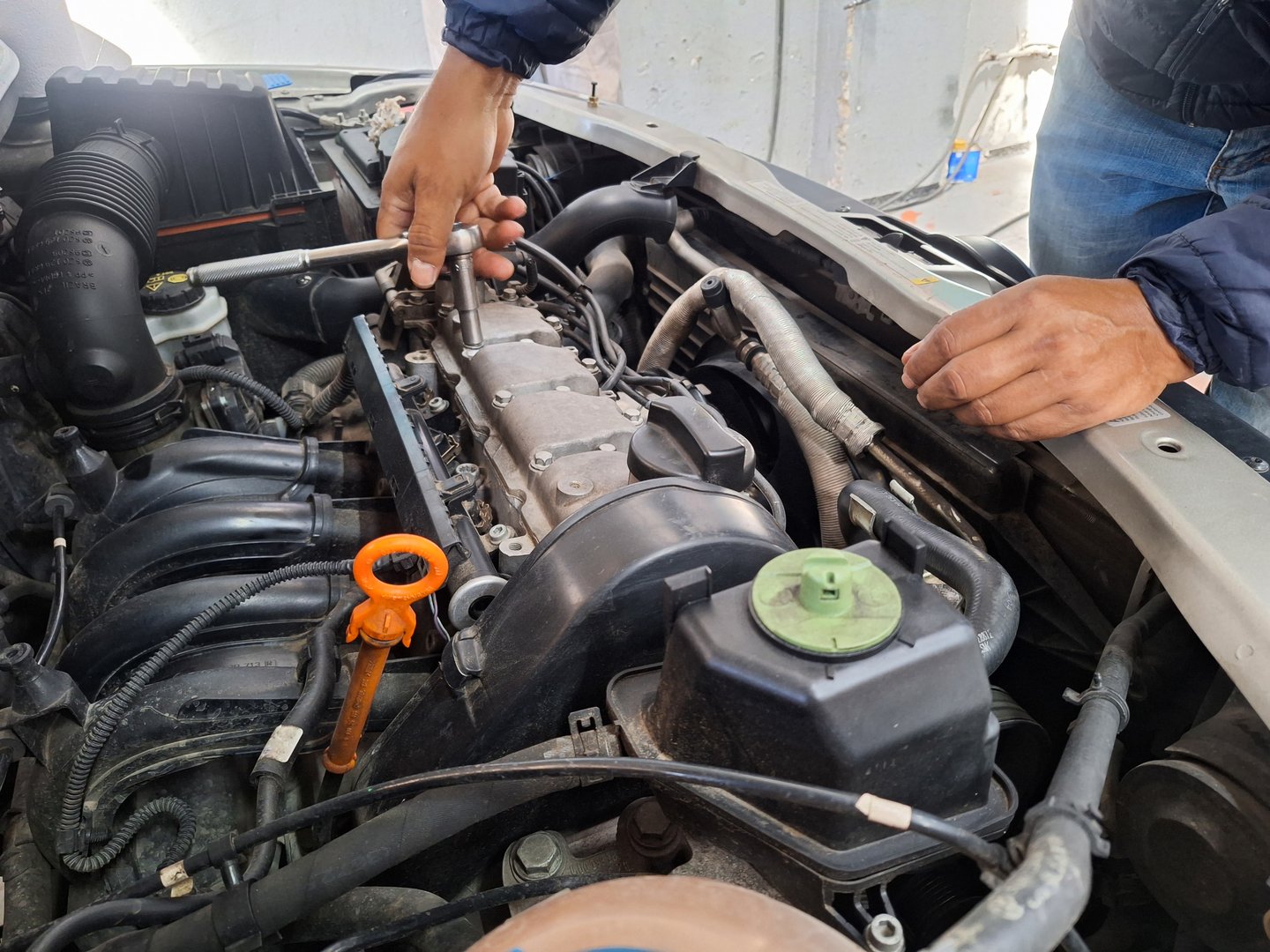 Close-up of a man closing the engine of a car with a wrench in an automotive workshop