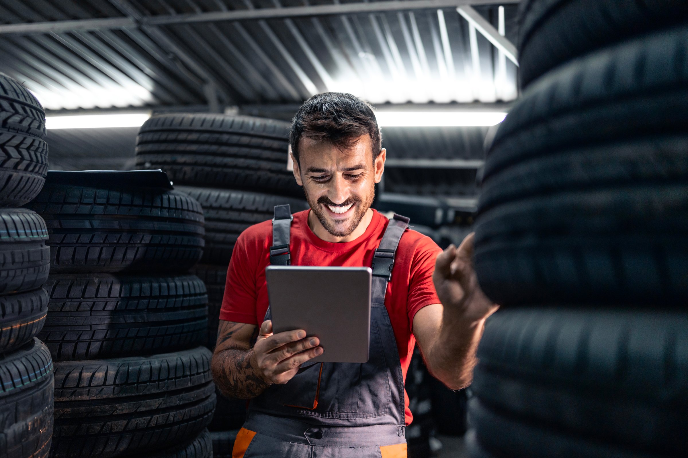 Warehouse worker holding tablet computer, checking inventory and searching for new tire.