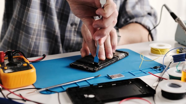 Master Technician In An Electronics Repair Service Center Is Fixing A Smartphone, Disassembling The Phone